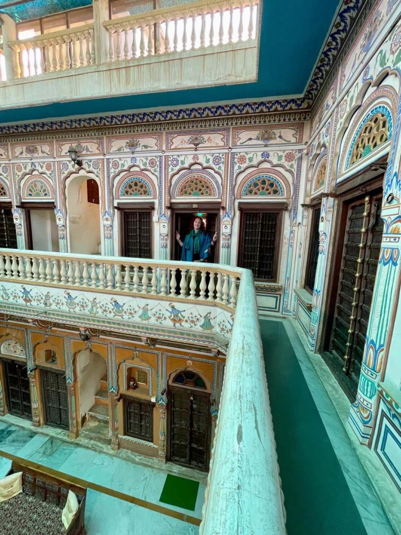 Guest on a frescoed balcony above a haveli courtyard in Nawalgarh