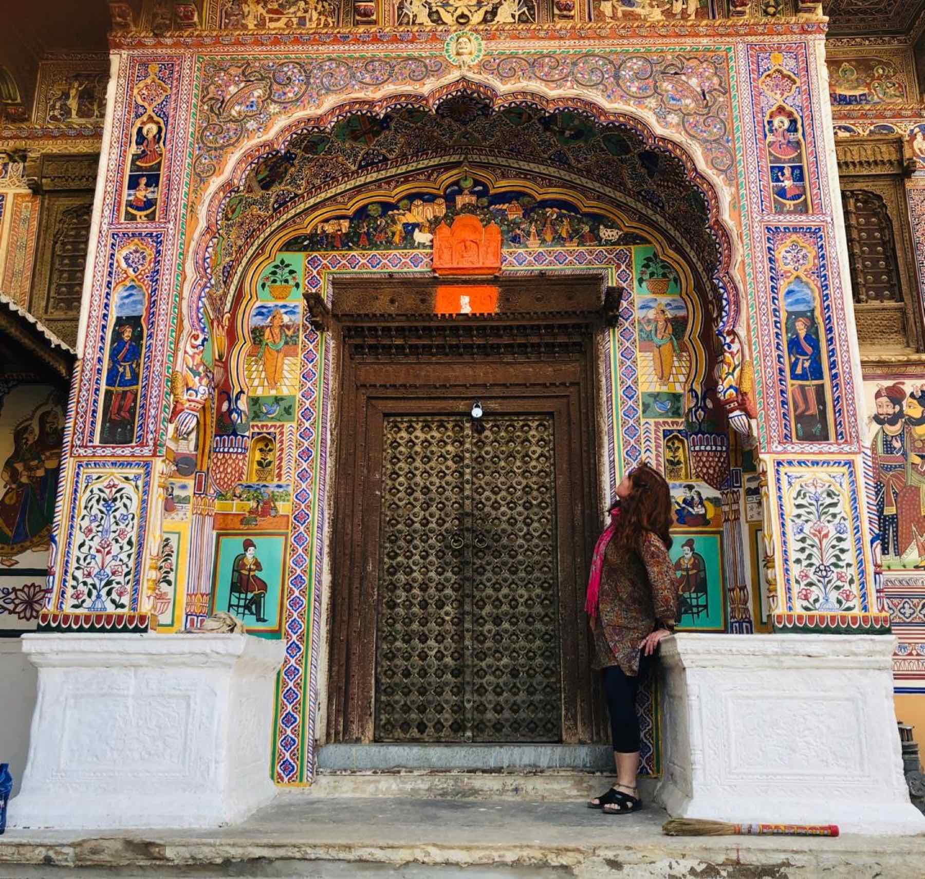 A guest at a painted haveli doorway in Shekhawati
